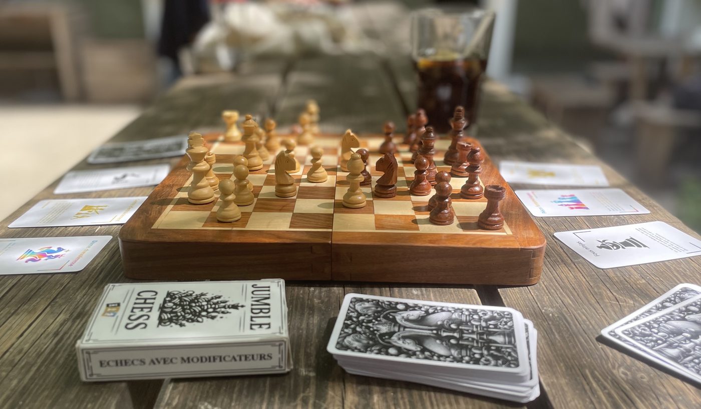 Tablero de madera rodeado de cartas de Jumble Chess y la caja del juego