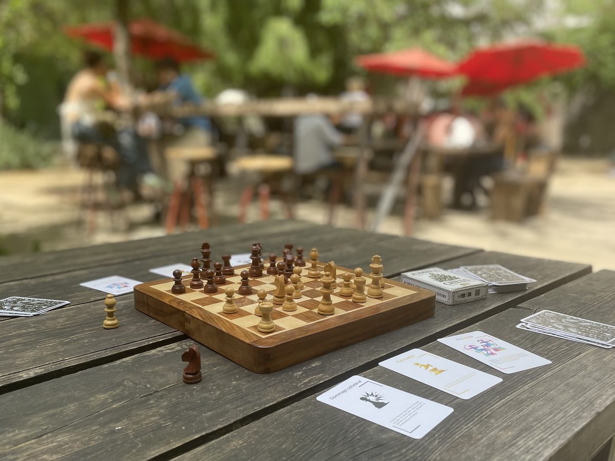 Partie de Jumble Chess en terrasse : échiquier et cartes modificateurs